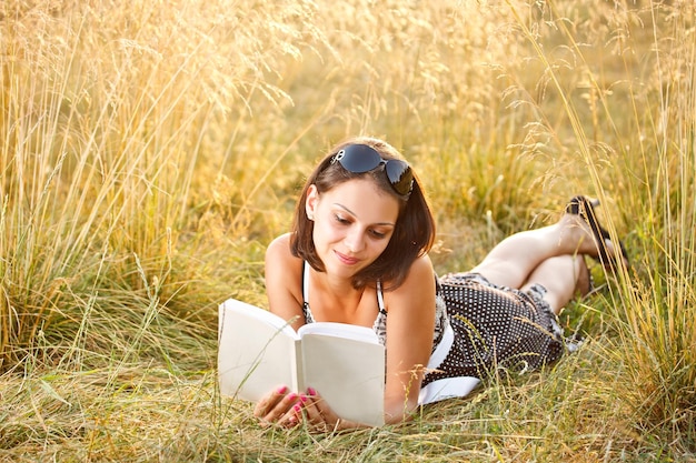 Woman lies on grass and reads book