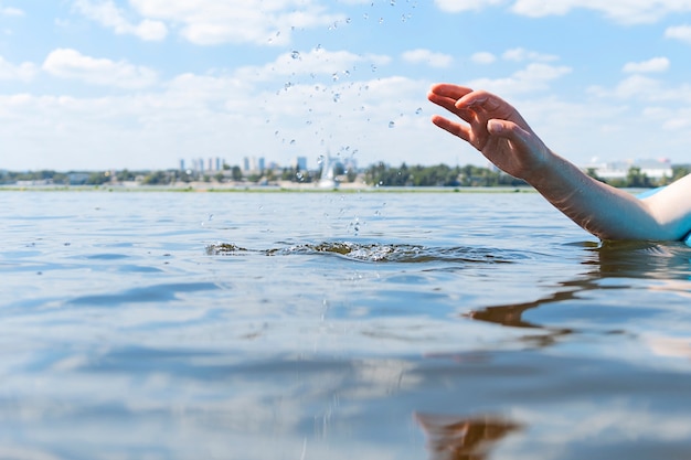 A woman lies on a paddle board on the river and sprays water with her hand