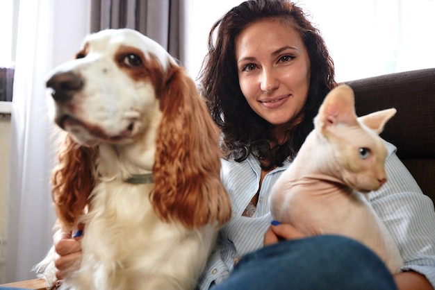 A woman lies on a sofa with a cat and a dog Love for pets concept