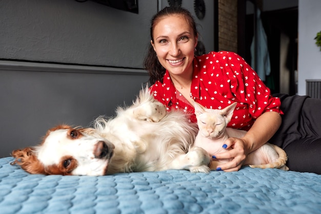 A woman lies on a sofa with a cat and a dog Love for pets concept