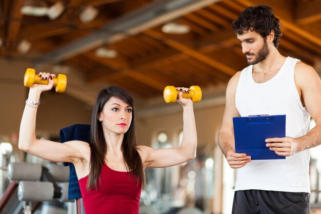 Woman lifting dumbbells with instructor