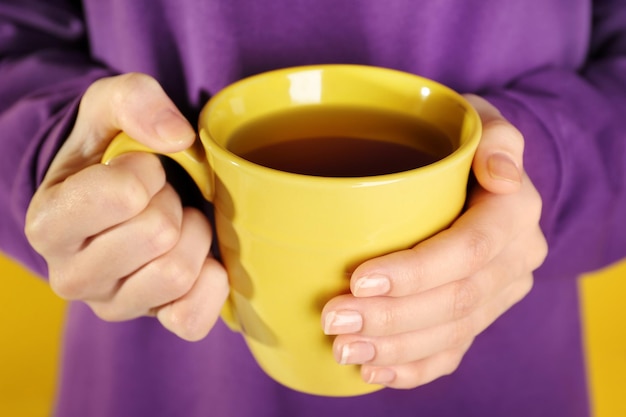 Woman in lilac color cloth holding cup closeup