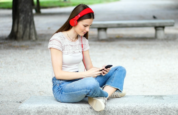 Woman listening to music sitting on bench in a park