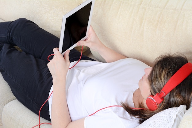 Woman listening music with digital tablet on the sofa.