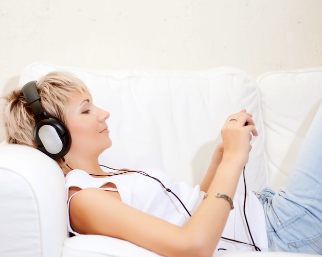 Woman in living room listening to MP3 player smiling