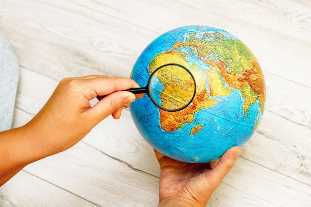 woman looking at Africa on a globe using a magnifying glass