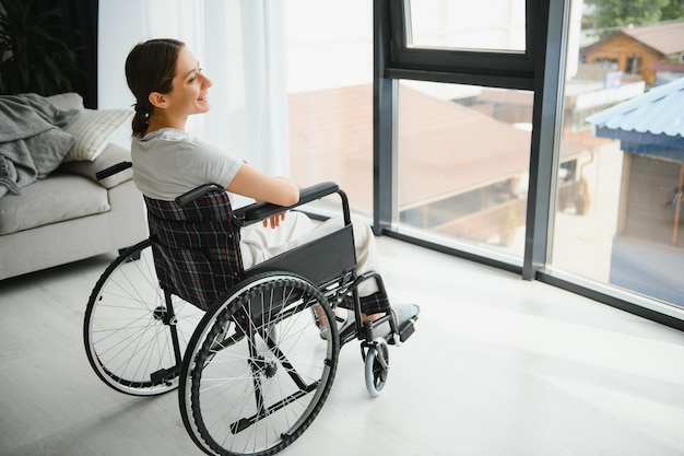 Woman looking away while sitting in wheelchair at home