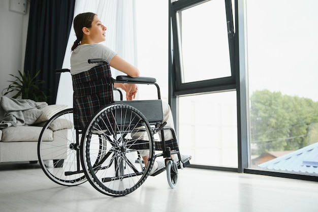 Woman looking away while sitting in wheelchair at home