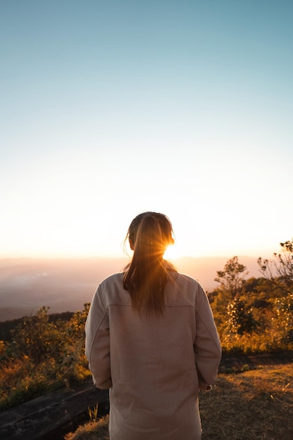 Woman looking at beautiful mountain valley in fog at sunrise in summer