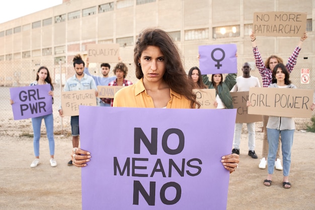 Woman looking at camera holding banner activists protestors feminism march demonstration