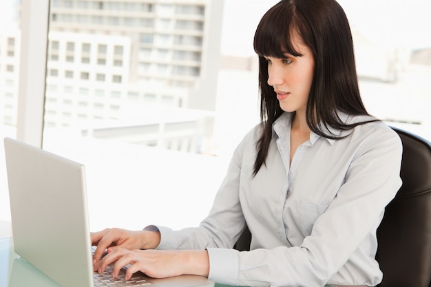 A woman looking at her laptop screen as she types