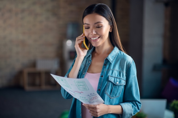 Woman looking at her notes while speaking on the phone