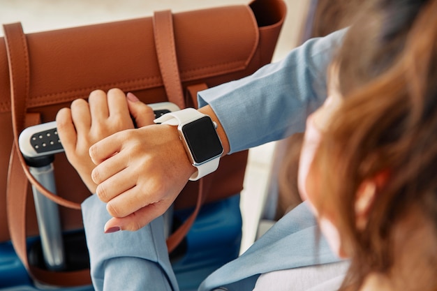 Woman looking at her smartwatch while at the airport during pandemic