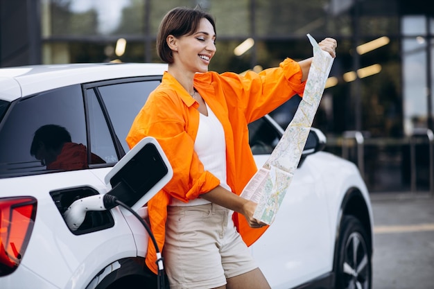 Woman looking at map while charging electric car