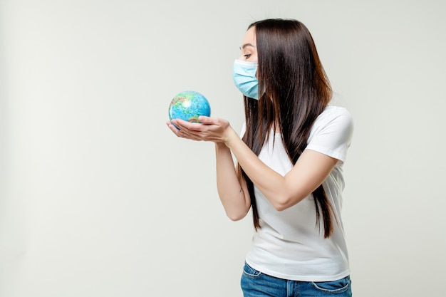 Woman looking at planet earth globe wearing mask