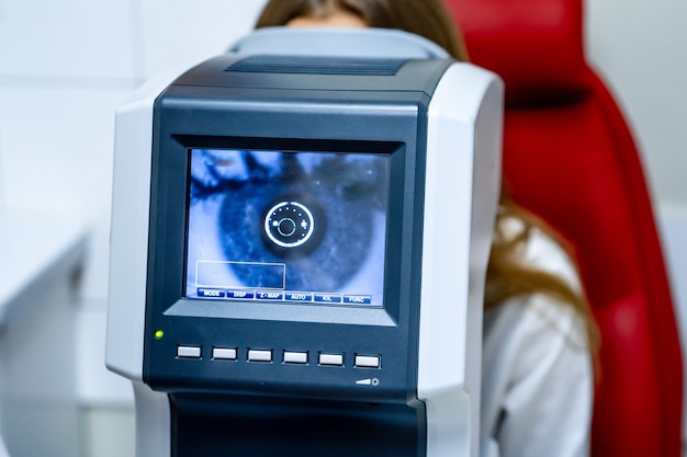 Woman looking at refractometer eye test machine in ophthalmology