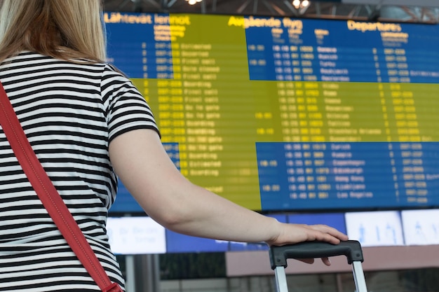 Photo woman looks at the scoreboard at the airport select a country sweden for travel or migration