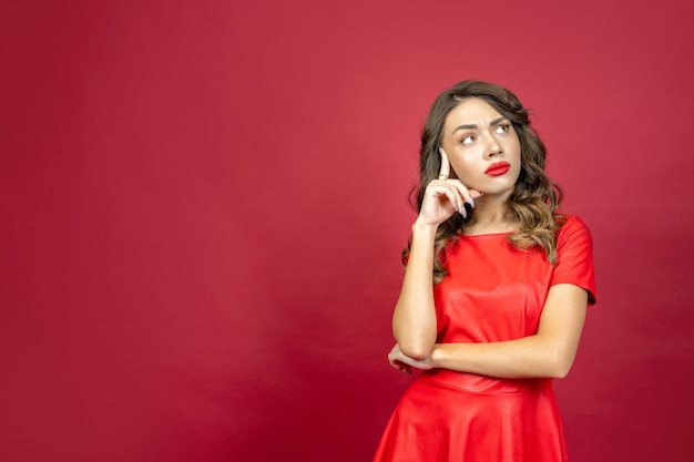 Woman looks thoughtfully on a red background