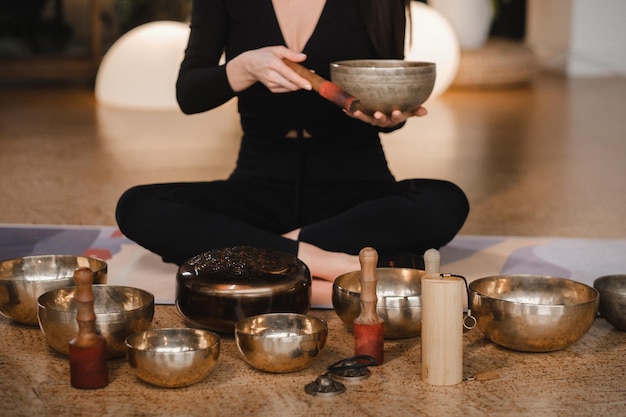 Photo a woman in the lotus position using a singing bowl indoors relaxation and meditation sound therapy alternative medicine buddhist healing practices