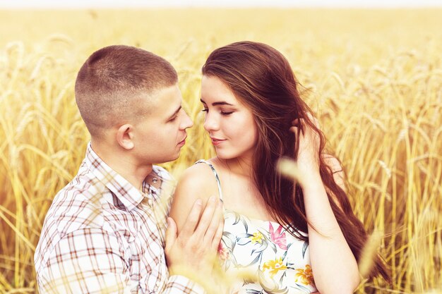 A woman in love and her boyfriend are hugging on a wheat field