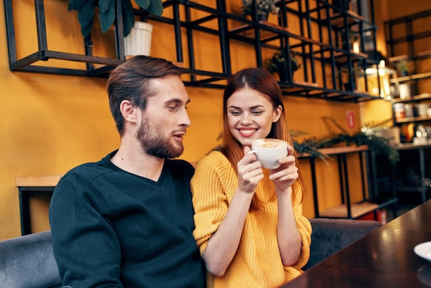 A woman in love with a cup of coffee and a happy man at a table in a cafe interior friends communication