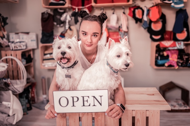 Photo woman loving pets. dark-eyed woman loving pets feeling amazing while opening shop for pets