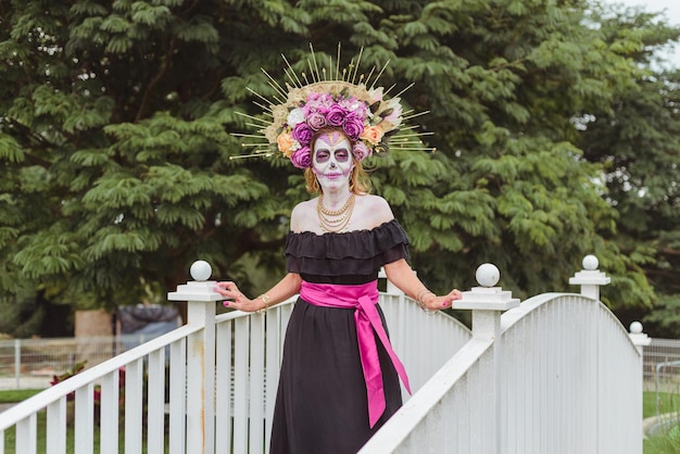 Woman made up as catrina. Mexican woman celebrating day of the dead. Outdoor portrait with Halloween makeup.