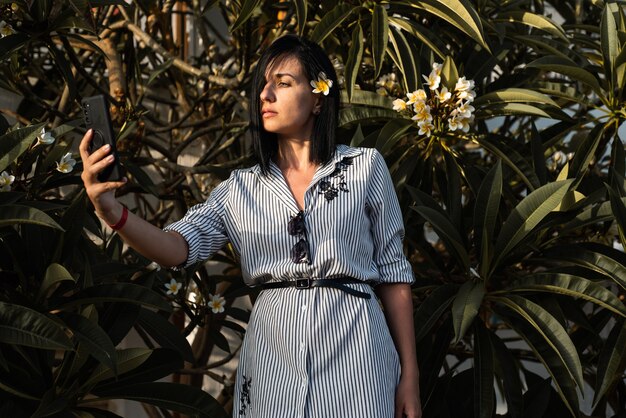 Woman make selfie in garden with flowers