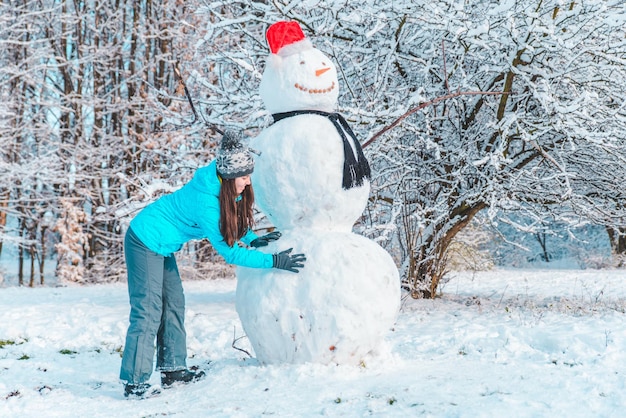 Photo woman make a snowman in frosty winter day concept