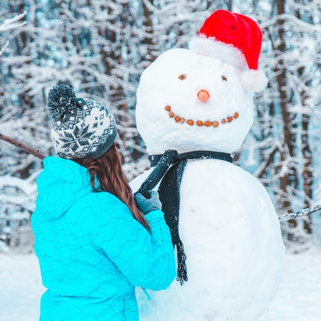 Woman make a snowman in frosty winter day concept