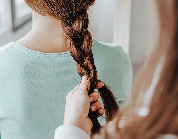 Woman makes a braid to her friend