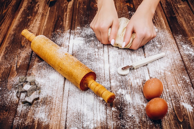 Woman makes Christmas pastry on the dough on wooden table 