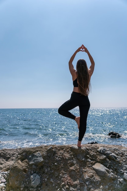 Woman makes heart with hands on beach young woman with long hair fitness instructor stretching