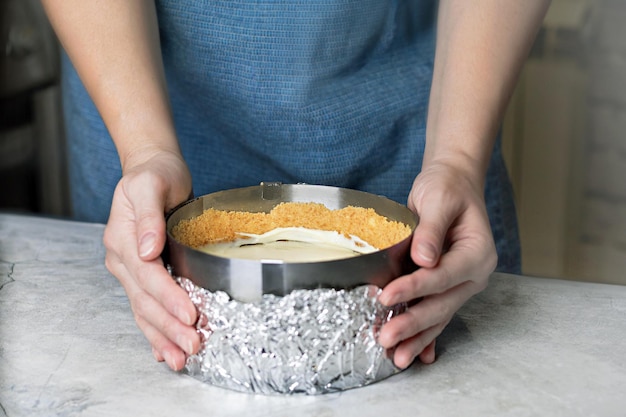 Woman making cheesecake making cheesecake in a baking form in the kitchen close up photo food