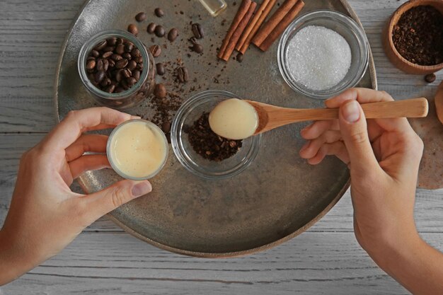 Woman making coffee body scrub on wooden table