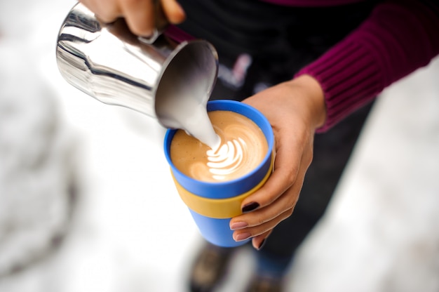 Woman making coffee latte art in coffee shop