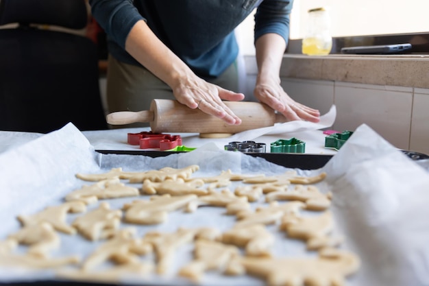 A woman making cookies in the shape of dinosaurs