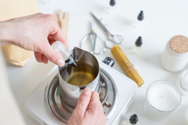 Woman making decorative aroma candle adding aroma closeup