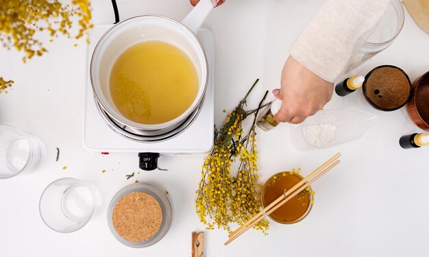 Woman making decorative aroma candle at table top view