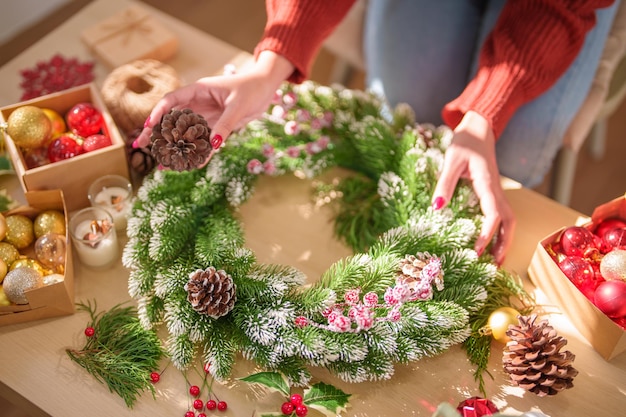 Photo woman making mistletoe wreath christmas wreath decoration with hand made diy winter greenery florist hands making christmas wreath beautiful mistletoe