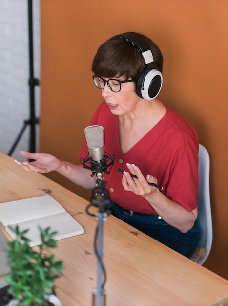 Woman making podcast recording for her online show Attractive business woman using headphones front of microphone for a radio broadcast