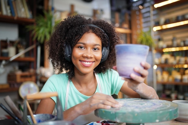 Woman making pottery in workshop Shaping wet clay on pottery wheel