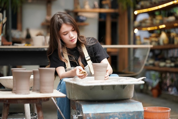 Woman making pottery in workshop Shaping wet clay on pottery wheel