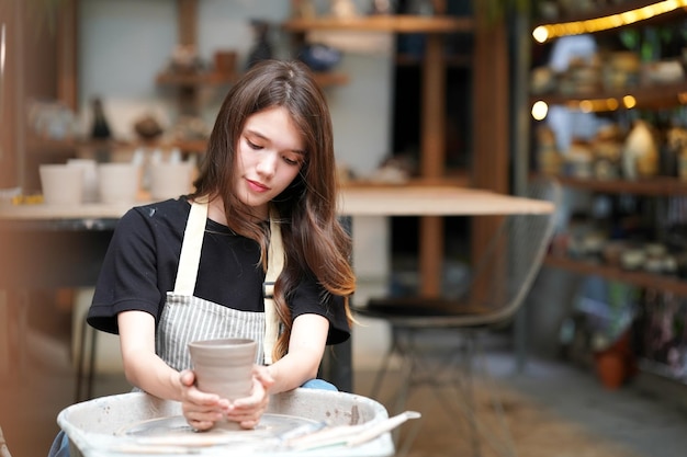 Woman making pottery in workshop Shaping wet clay on pottery wheel