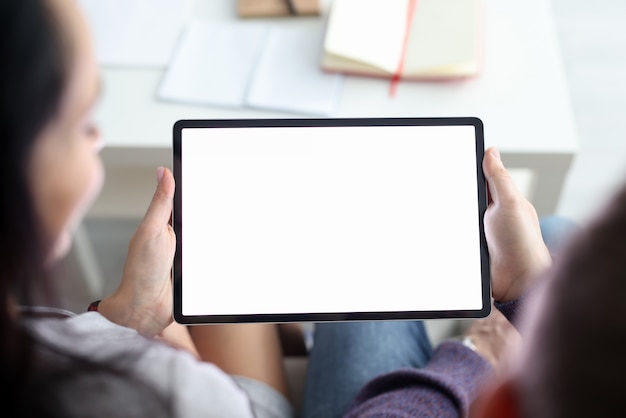 Woman and man are sitting on couch at home and holding tablet in their hands closeup family