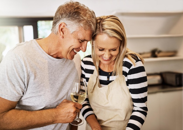 Photo woman man and dinner in home with wine cheerful and romantic for connection relationship and bonding as couple happy people smile and cheers for meal celebration or anniversary in kitchen