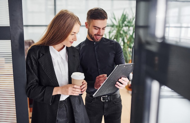 Woman and man in formal clothes with documents talking to each other in the office.