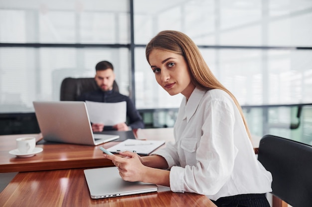 Woman and man in formal clothes working together indoors in the office by table with documents.