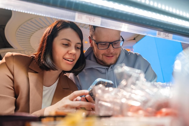 Woman and man looking for Products on Shelf Couple Customers Shopping With Checklist