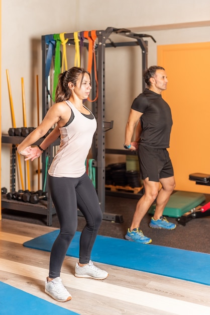 Woman and man stretching arms back in gym. Concept of exercises in gym.